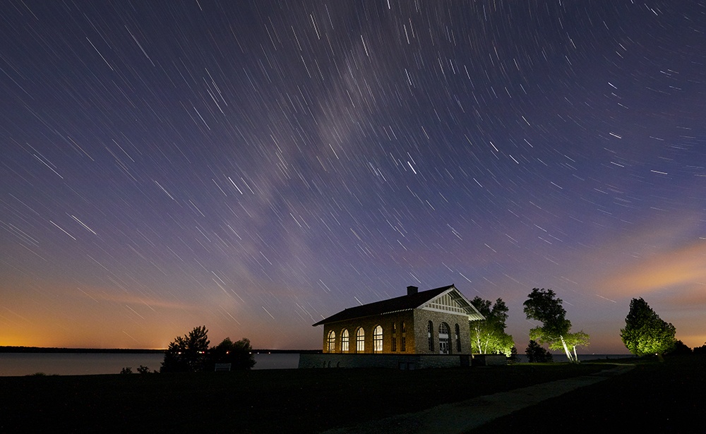 A remote boathouse illuminated by the purples and oranges of the Northern Lights