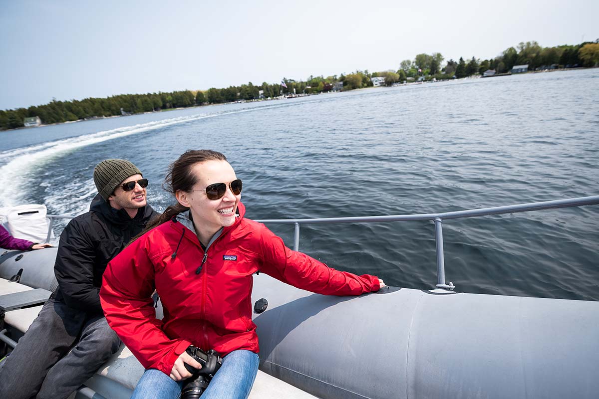 A woman and man ride away from an island on a speeding boat.