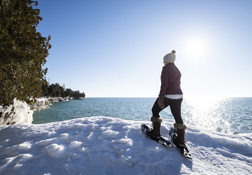 A snowshoer standing and looking out over the lake.