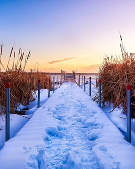 Foot prints in the snow on a boardwalk.