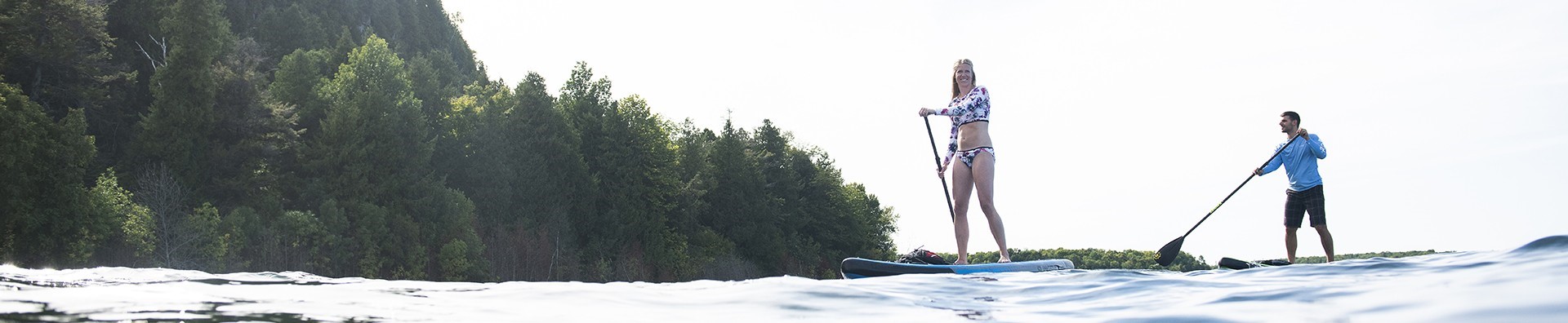 A man and woman on standup paddleboards just off shore