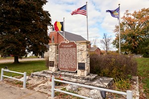 Historical marker in front of flags.