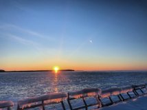 Iced over pier railings with a sunset over the lake in the background