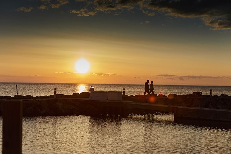 People walking out on a dock at sunset.