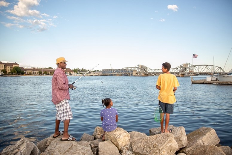 A dad and his kids fishing off large rocks.