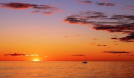 A lone sailboat on the lake at sunrise