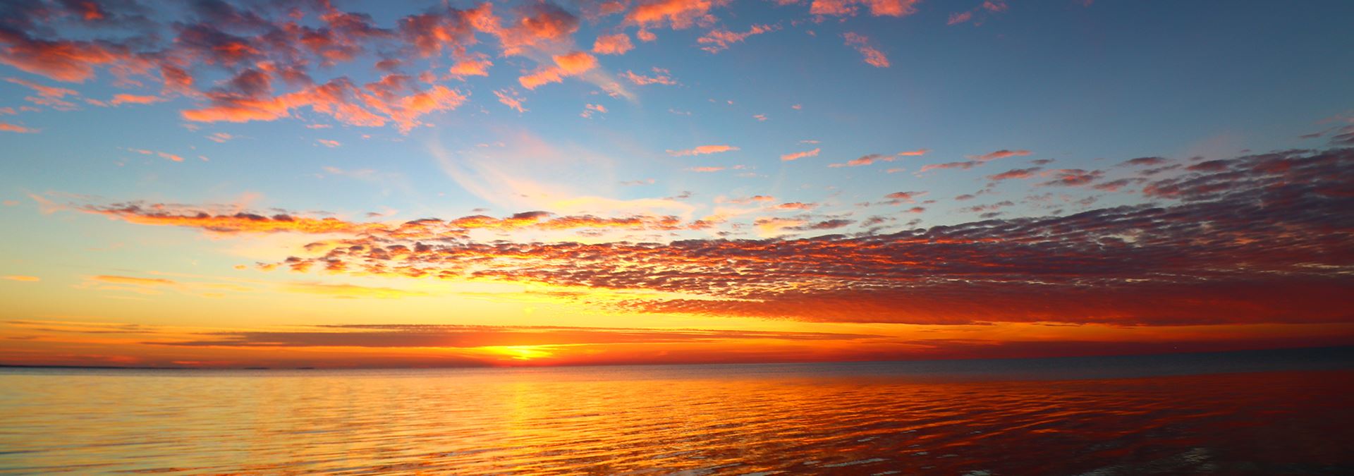 The sun setting over the lake and clouds.