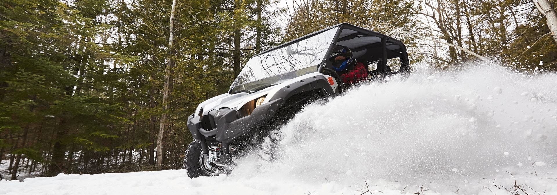 An ATV driving through the snow kicking up a cloud of snow.