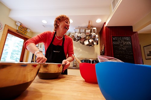 A woman cooking near several mixing bowls.