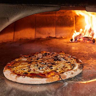 A pizza coming out of a brick oven