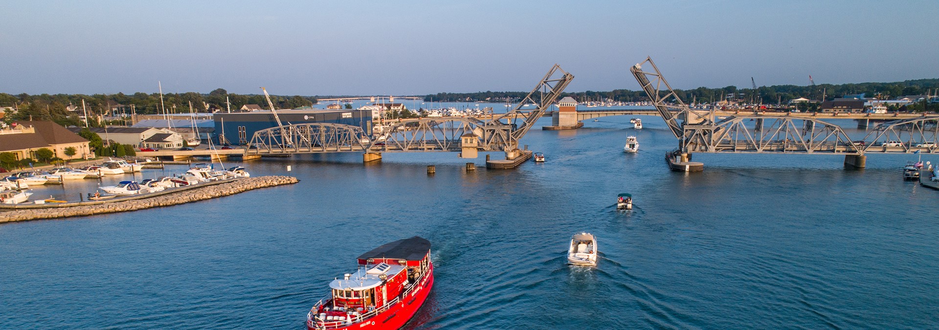 Boats lined up to go under a drawbridge.