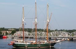 Tall sailing ship in front of a steel bridge.