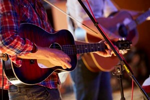 Closeup of people playing acoustic guitars.