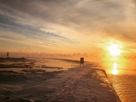 The sun rising over the snowy lakefront.