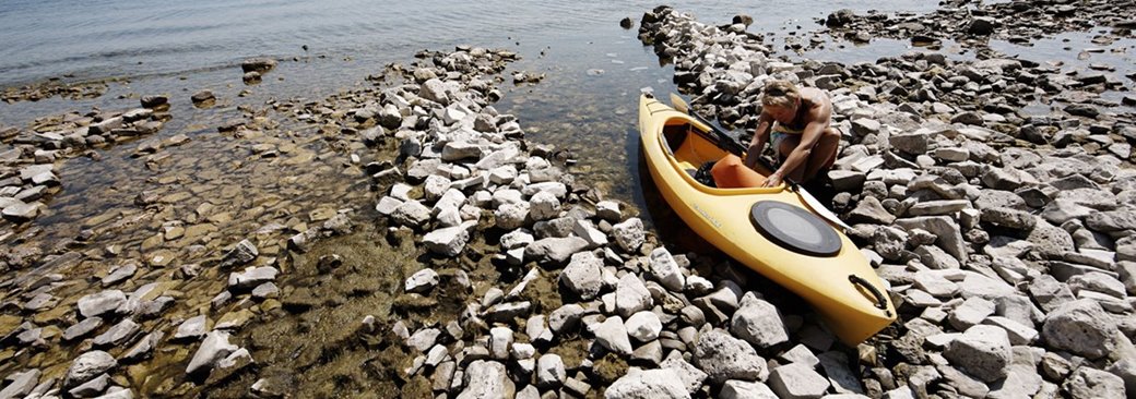 A person preparing to launch a kayak into the lake.