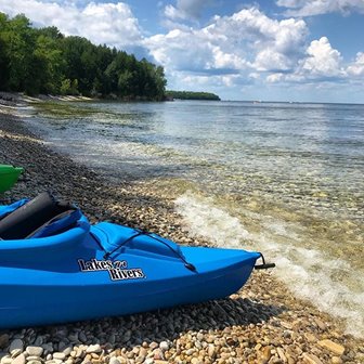 A close up of the side of the front of a kayak on the beach near the water