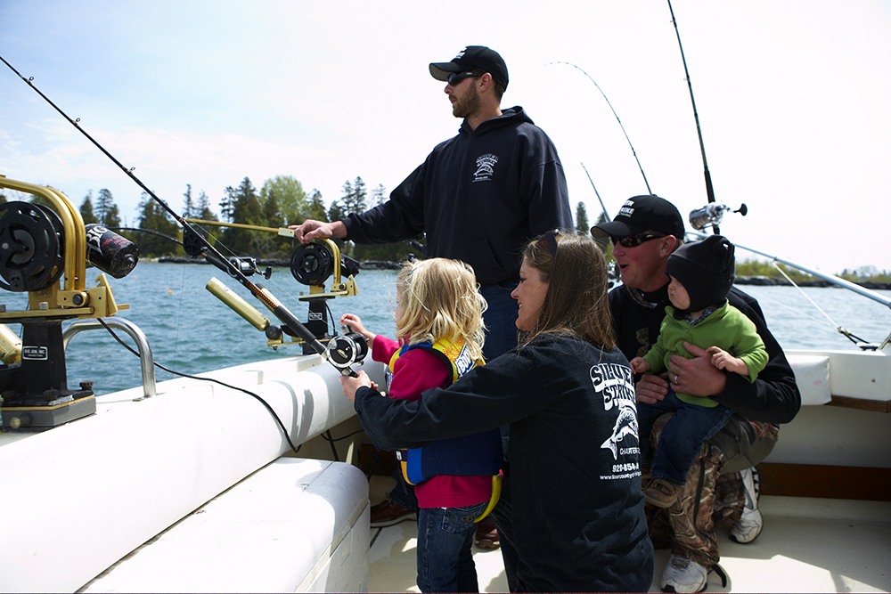 A fishing guide assists a family with kids at they cast off the boat.