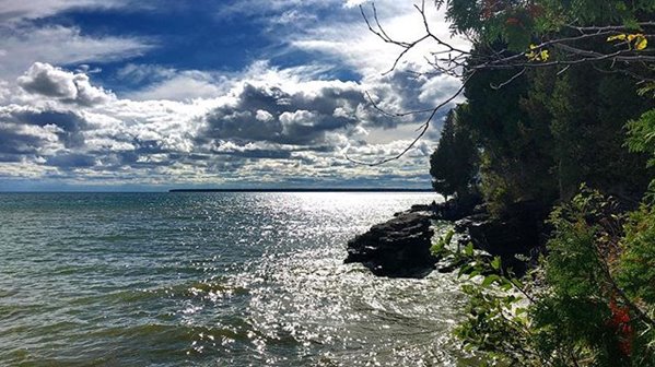 Sunny and cloudy sky over the lake near cliffs