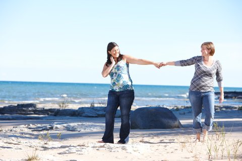 Couple holding hands on the beach and smiling at each other