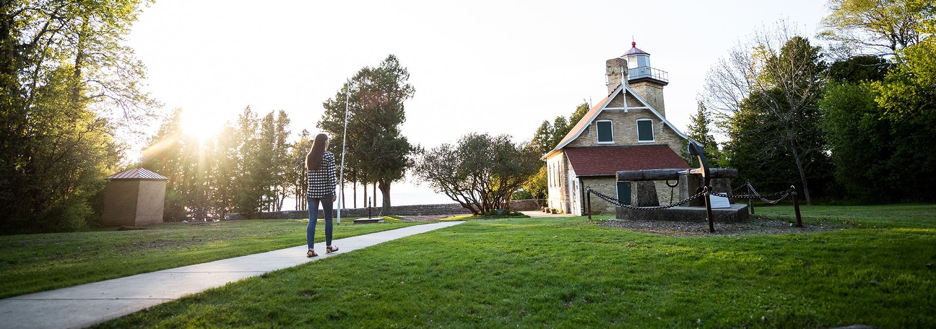 A woman walking up a path to a lighthouse.