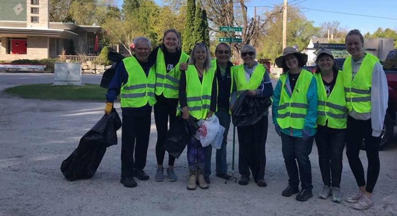 Volunteer cleanup crew in reflective vests posing for a group picture.