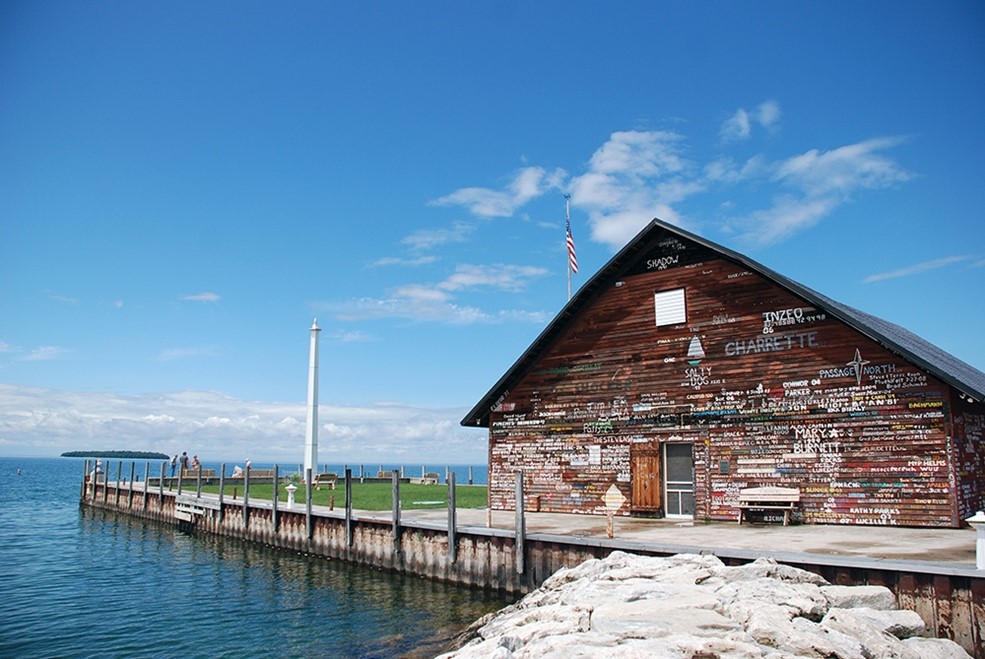 Wood building with painted words all over it next to the lake.