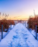 The sun low in the sky over a snowy pier.