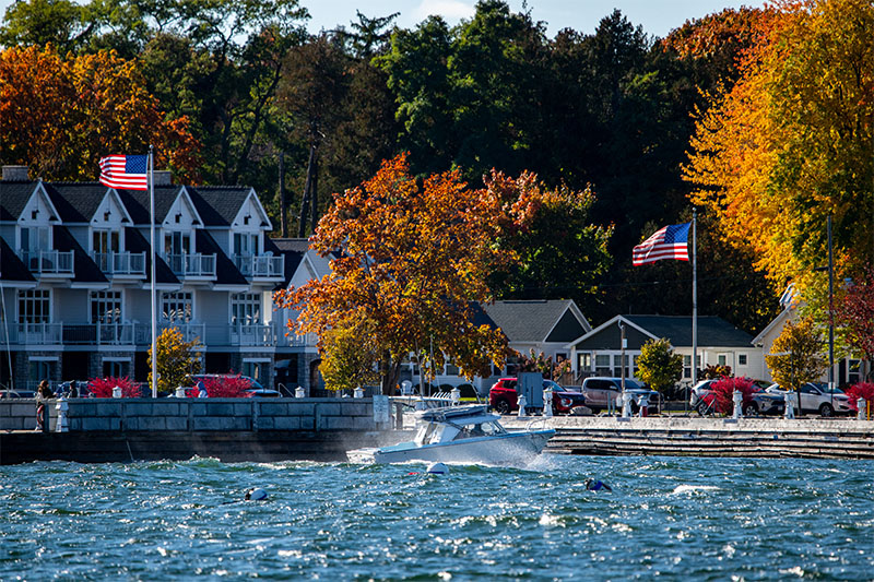 A boat cruises through the water in Door County, along the shore lined with condos and cars.