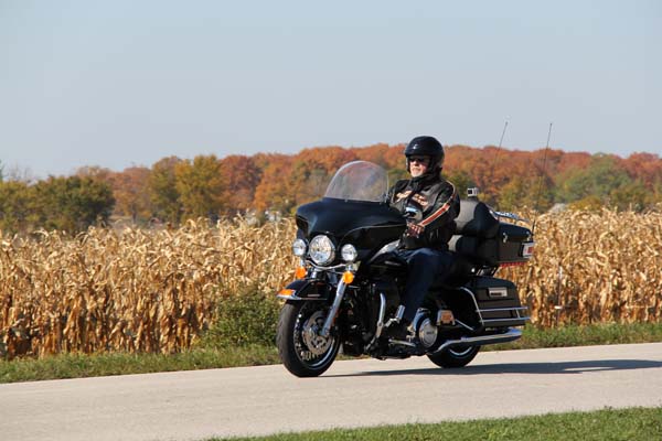 A motorcyclist riding through cornfields in fall.