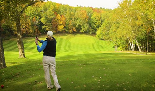 A woman watches her ball fly through the air after teeing off.