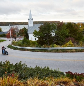 A white church with a steeple in the distance beyond a road.